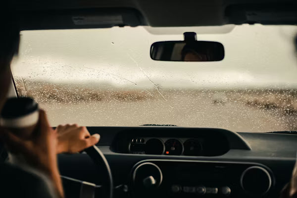 A car tires splashing through standing water on a highway during heavy rain.