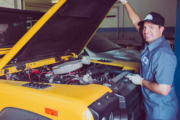 A vehicle owner performing routine maintenance under the open hood of a 2012 passenger sedan.